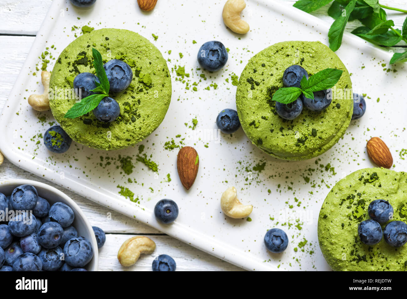 Hausgemachte raw Matcha Pulver Kuchen mit frischen Beeren, Minze, Muttern. Gesunde vegane Ernährung Konzept. top View Stockfoto