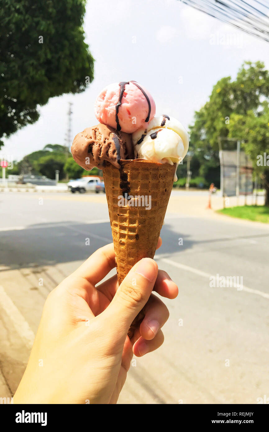 Hand, Schokolade, Vanille und Erdbeere Eis im Sommer oder heißem Wetter. Stockfoto