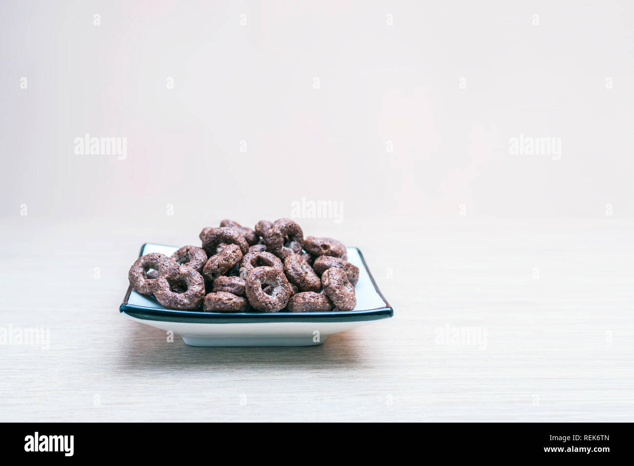 Crunchy Vollkorn Schoko Müsli, Hafer in einem quadratischen Teller auf hellem Holz Tisch. Gesunde organische Snack, Essen, Frühstück Konzept mit Copy-Spac Stockfoto