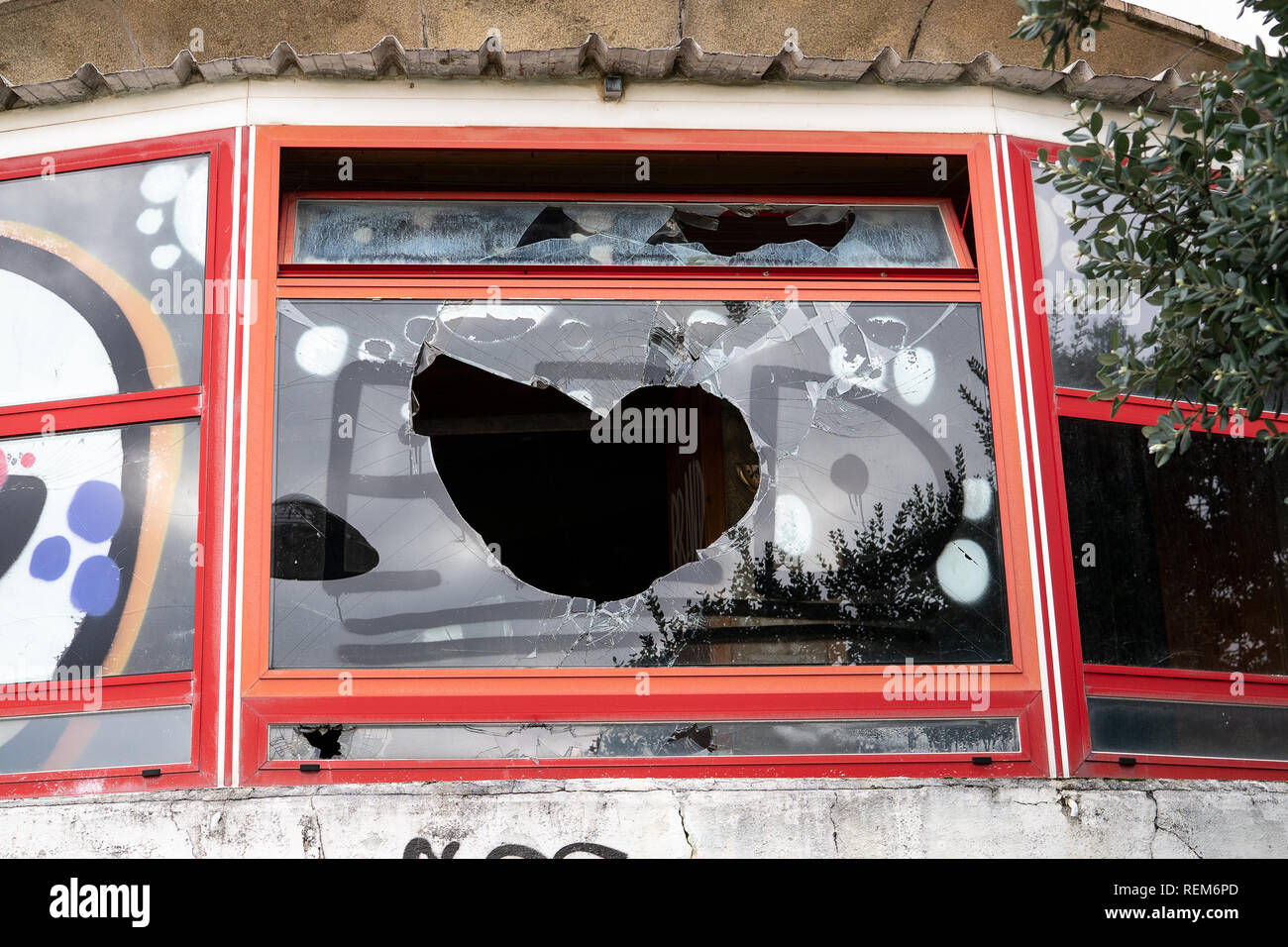 Vandalismus Konzept. Gebäude mit gebrochenen Fenster und Graffiti. Vandal Graffiti auf dem Fenster eines Hauses Stockfoto