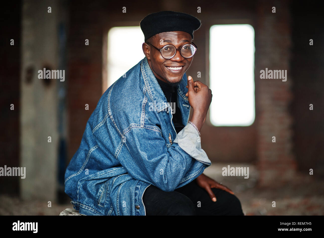 Afrikanische amerikanische Mann in Jeans Jacke, Baskenmütze und Brillen an verlassenen Ziegelei. Stockfoto