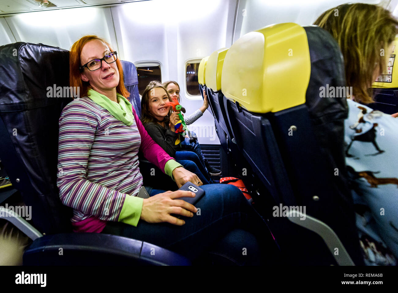 Familie sitzt auf Ledersitze in Verkehrsflugzeugen. Mutter und Töchter sitzen auf einer low cost Airlines Jet plane. Stockfoto