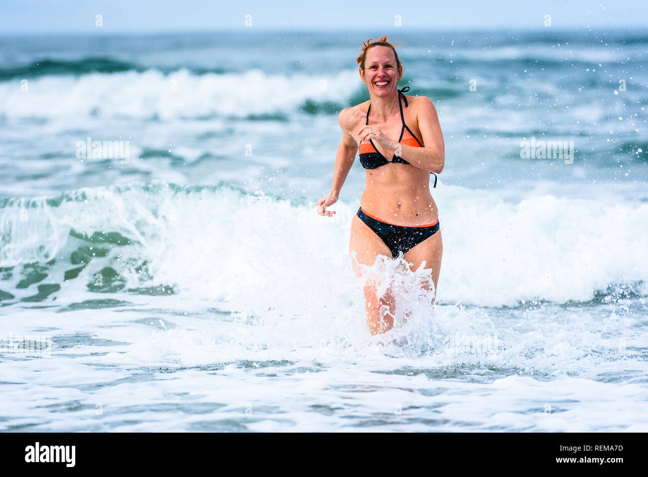 Frau genießen das Meer und die Wellen des Atlantik. Reife, mittlere Alter, junge attraktive Frau im Badeanzug Bikini läuft im Ozean Meer, Verscherzen Stockfoto