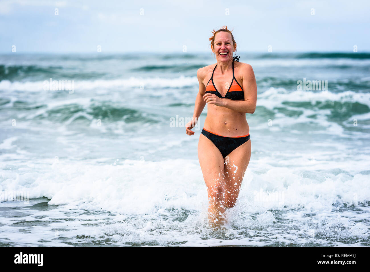 Frau genießen das Meer und die Wellen des Atlantik. Reife, mittlere Alter, junge attraktive Frau im Badeanzug Bikini läuft im Ozean Meer, Verscherzen Stockfoto
