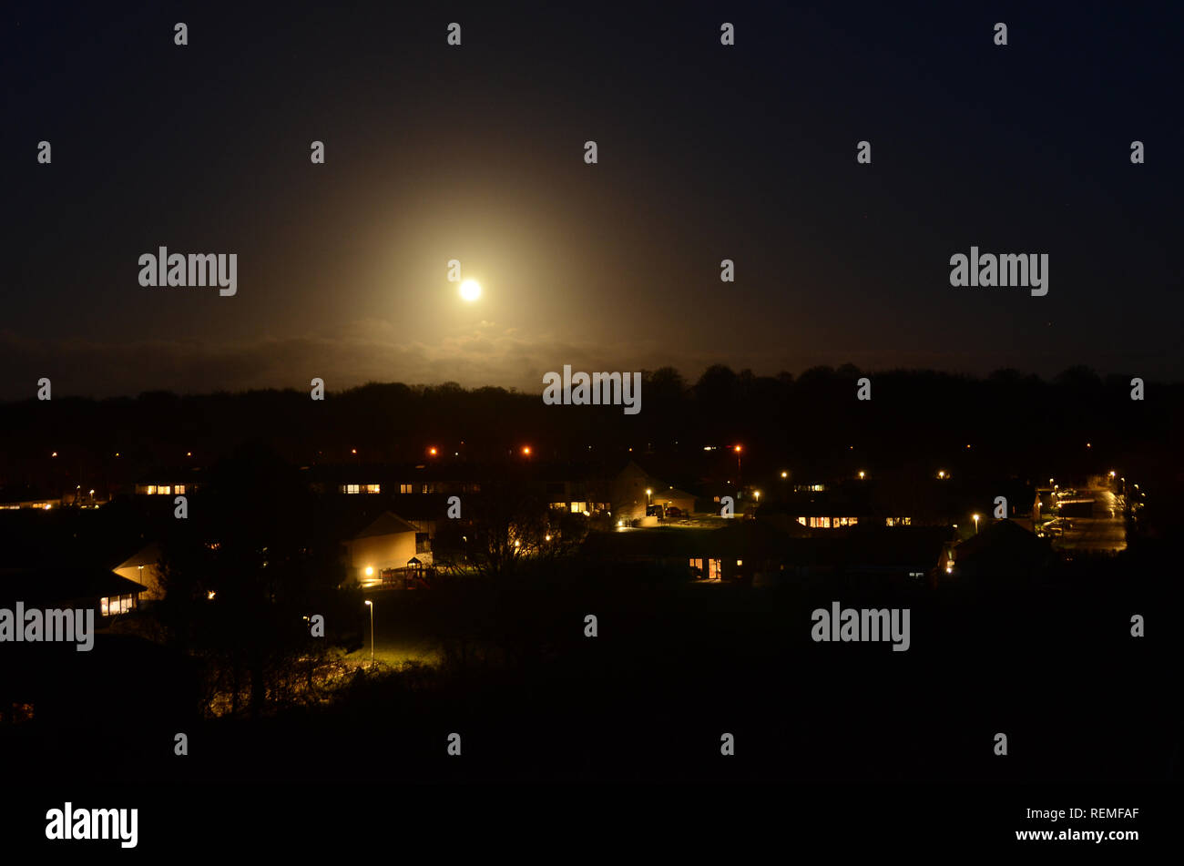 Nacht Blick über eine Siedlung mit einem aufgehenden Vollmond. Stockfoto