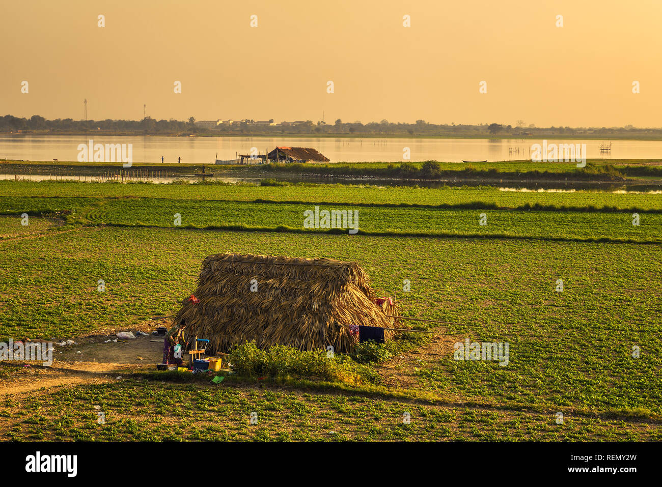 Burmesischen Frau zieht Wasser aus einem Brunnen bei Sonnenuntergang in Mandalay, Myanmar Stockfoto