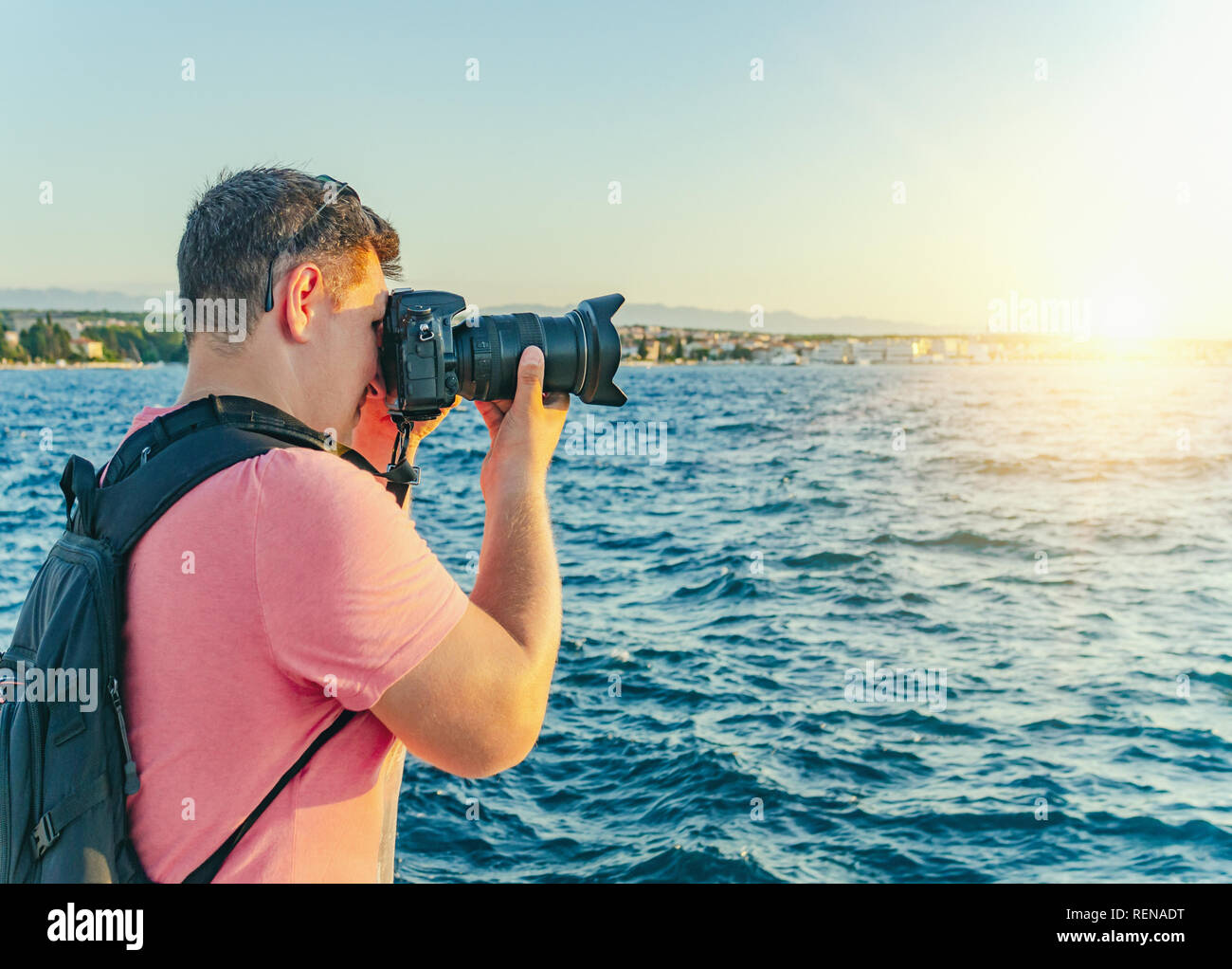 Der Mann mit der Kamera fotografieren den Sonnenuntergang an der Küste. Stockfoto