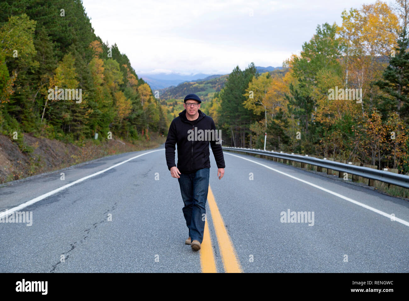 Ein Mann zu Fuß auf einem Highway in der gaspé Halbinsel von Quebec, Kanada. Er schreitet in der Mitte der Straße. Stockfoto