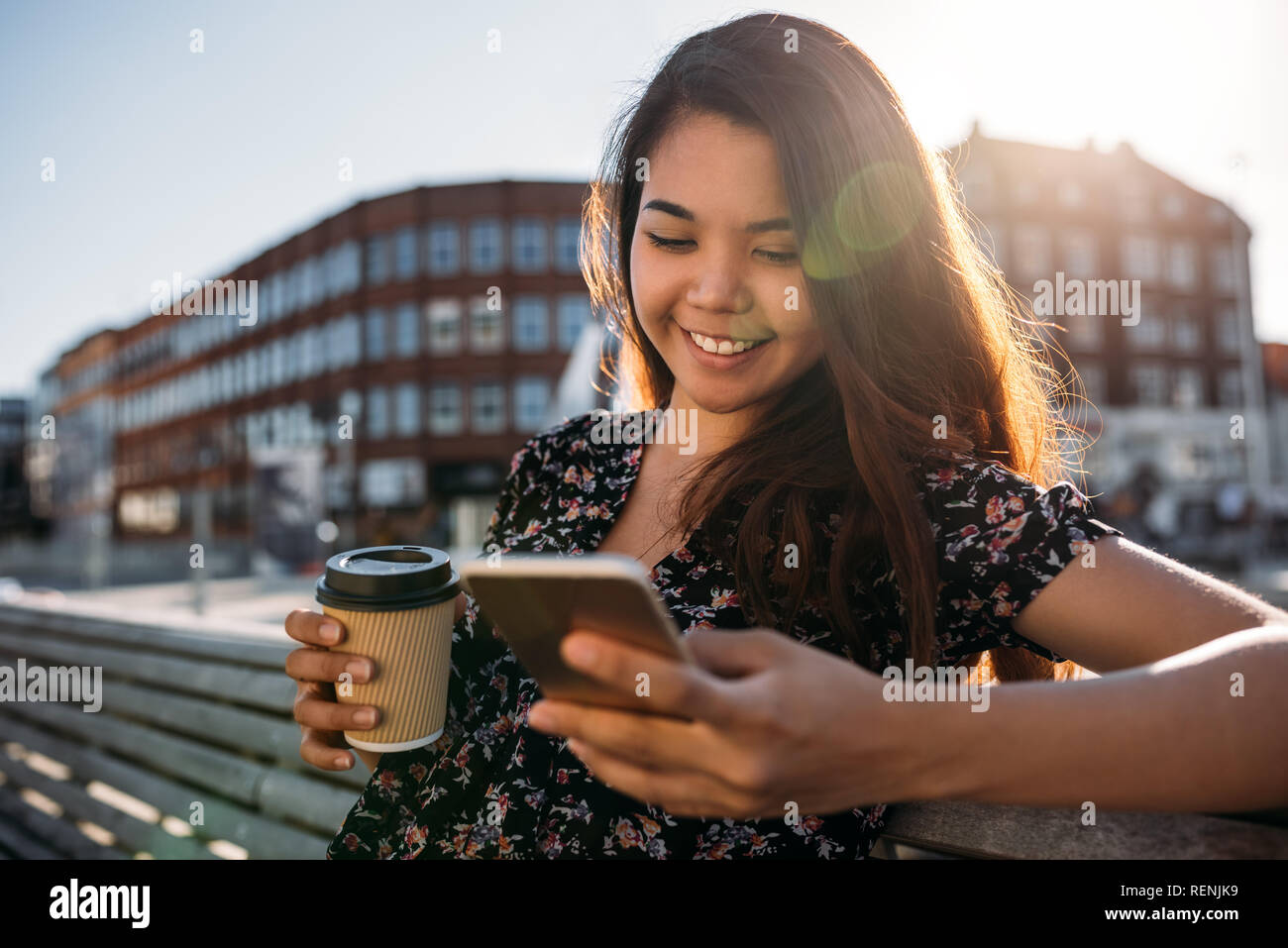 Lächelnd asiatische Studenten sitzen auf dem Campus einen Text senden Stockfoto