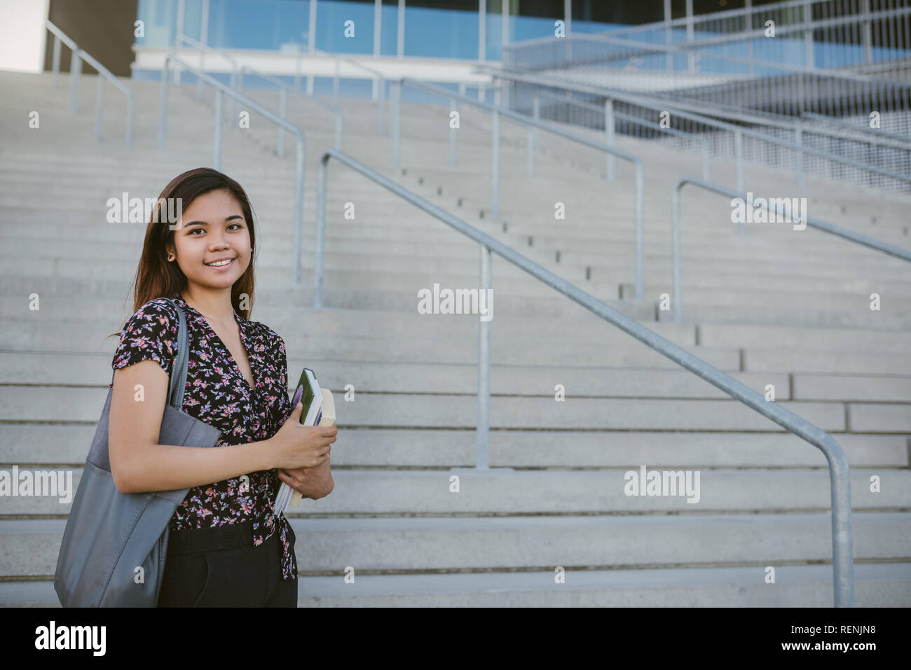 Lächelnden jungen asiatischen Studenten durch Campus Schritte stehen Stockfoto
