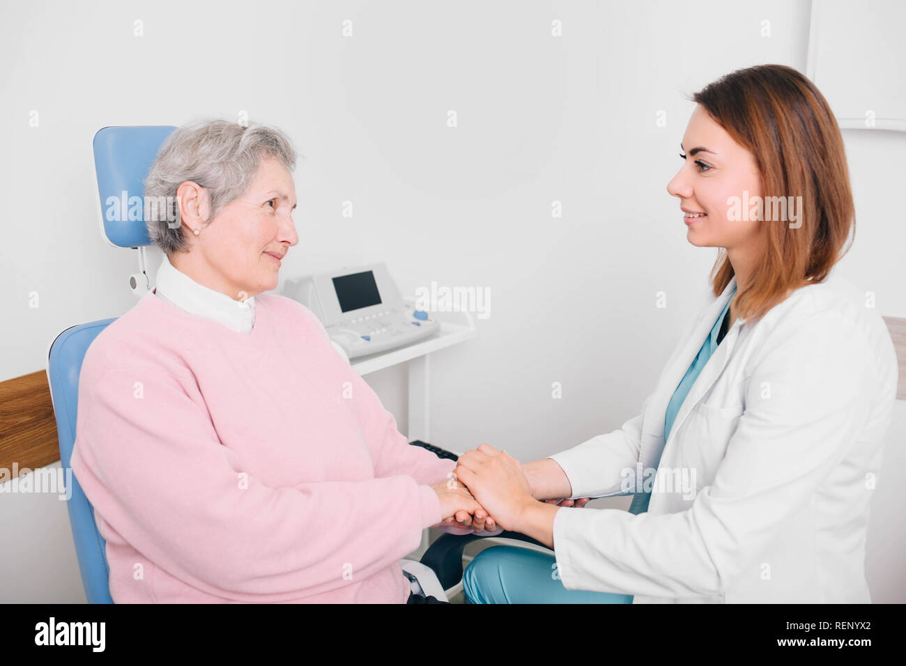 Arzt im Gespräch mit älteren Patienten und die Hand, Unterstützung Geste Stockfoto