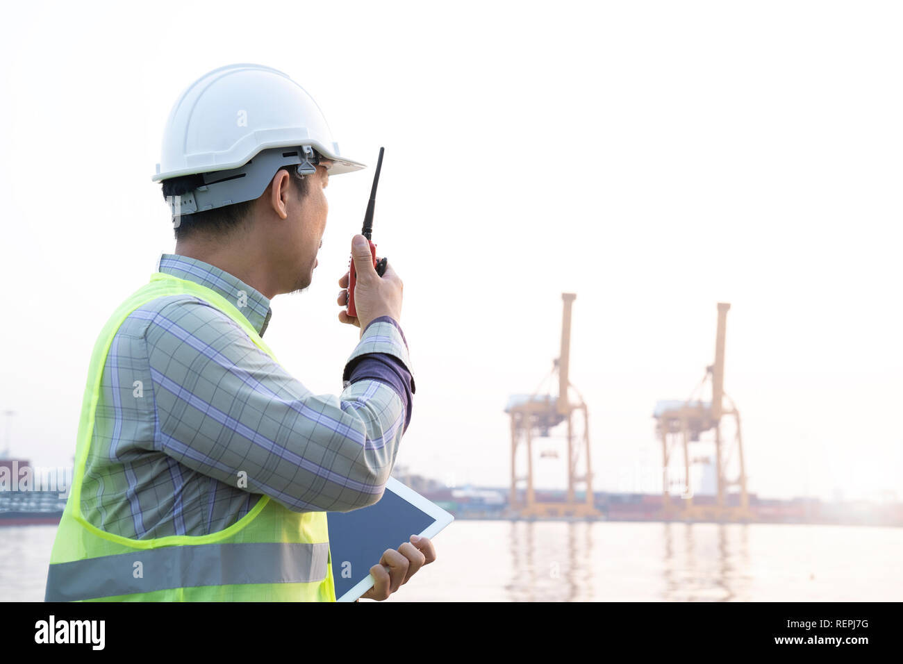 Asiatischer mann Ingenieur radio und Tablet und Arbeiten mit container Cargo Fracht Schiff in der Werft für Logistik Import Export Hintergrund, Sicherheit. E Stockfoto