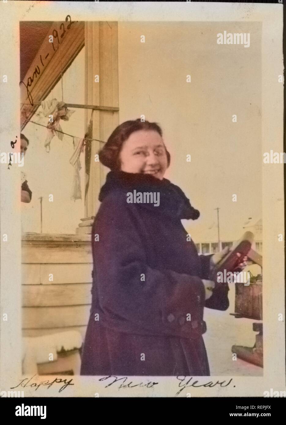 Junge Frau lächelt und schaut über ihre Schulter am Neujahrstag halten Sie ein Medium Format falten Kamera, 1922. Hinweis: Das Bild hat digital über ein modernes Prozess eingefärbt worden. Farben möglicherweise nicht sein - genau. () Stockfoto