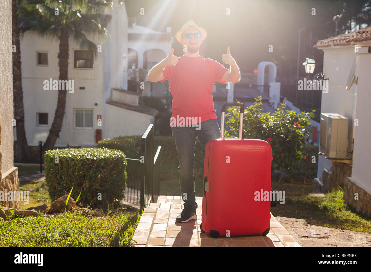Urlaub, Reisen und Ferien Konzept - stattlicher Mann mit roten Koffer am Hotel angekommen Stockfoto