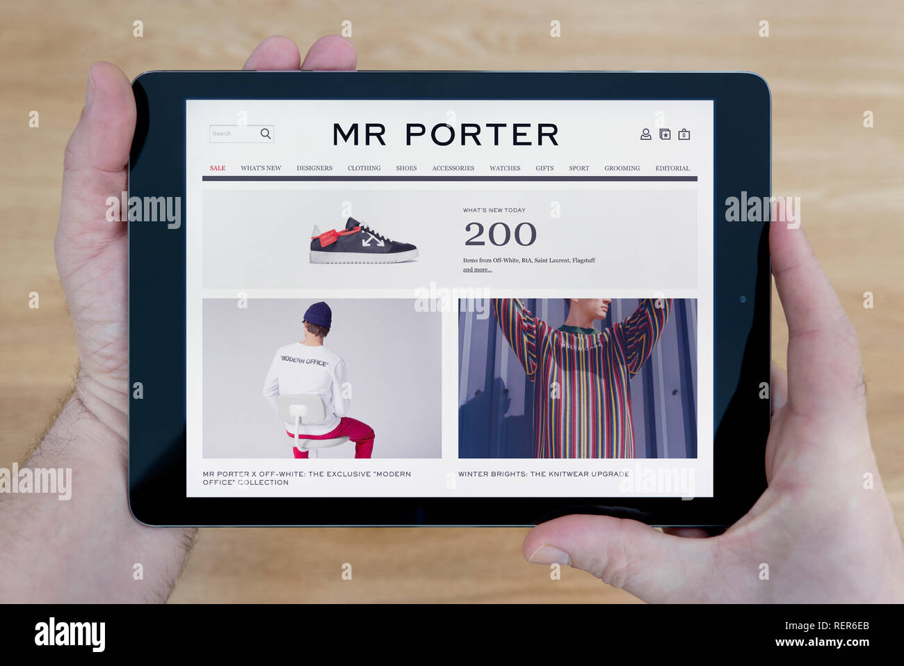 Ein Mensch sieht auf das, was Herr Porter Website auf seinem iPad tablet device, Schuß gegen einen hölzernen Tisch top Hintergrund (nur redaktionelle Nutzung) Stockfoto