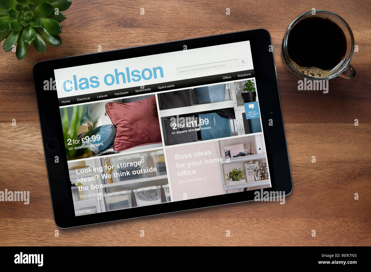Die Website von Clas Ohlson ist auf einem iPad Tablet gesehen, auf einer hölzernen Tisch zusammen mit einem Espresso und einem Haus Anlage (nur redaktionelle Nutzung). Stockfoto