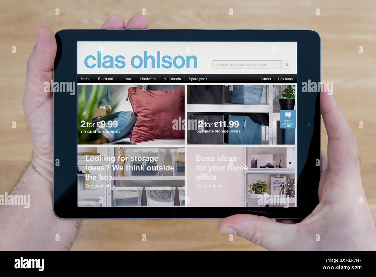 Ein Mann schaut auf die Clas Ohlson Website auf seinem iPad tablet device, Schuß gegen einen hölzernen Tisch top Hintergrund (nur redaktionelle Nutzung) Stockfoto