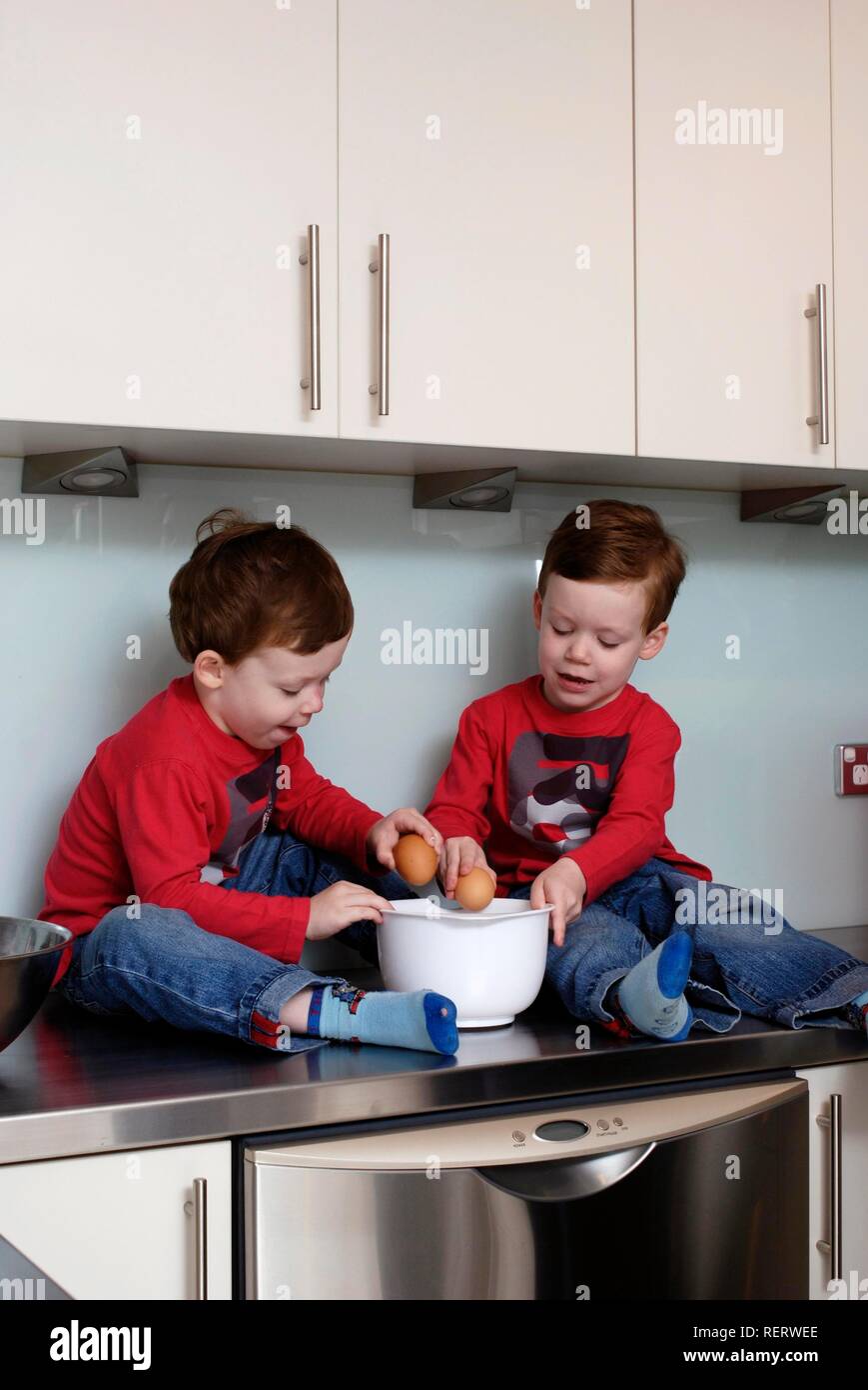 Zwillinge, Dreieinhalb Jahre, sitzen auf den küche top einige Backen zu tun Stockfoto