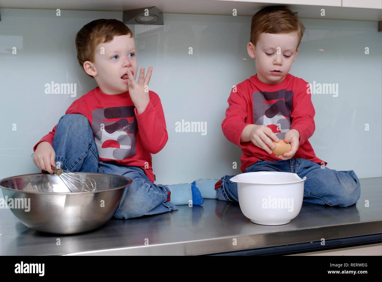 Zwillinge, Dreieinhalb Jahre, sitzen auf den küche top einige Backen zu tun Stockfoto