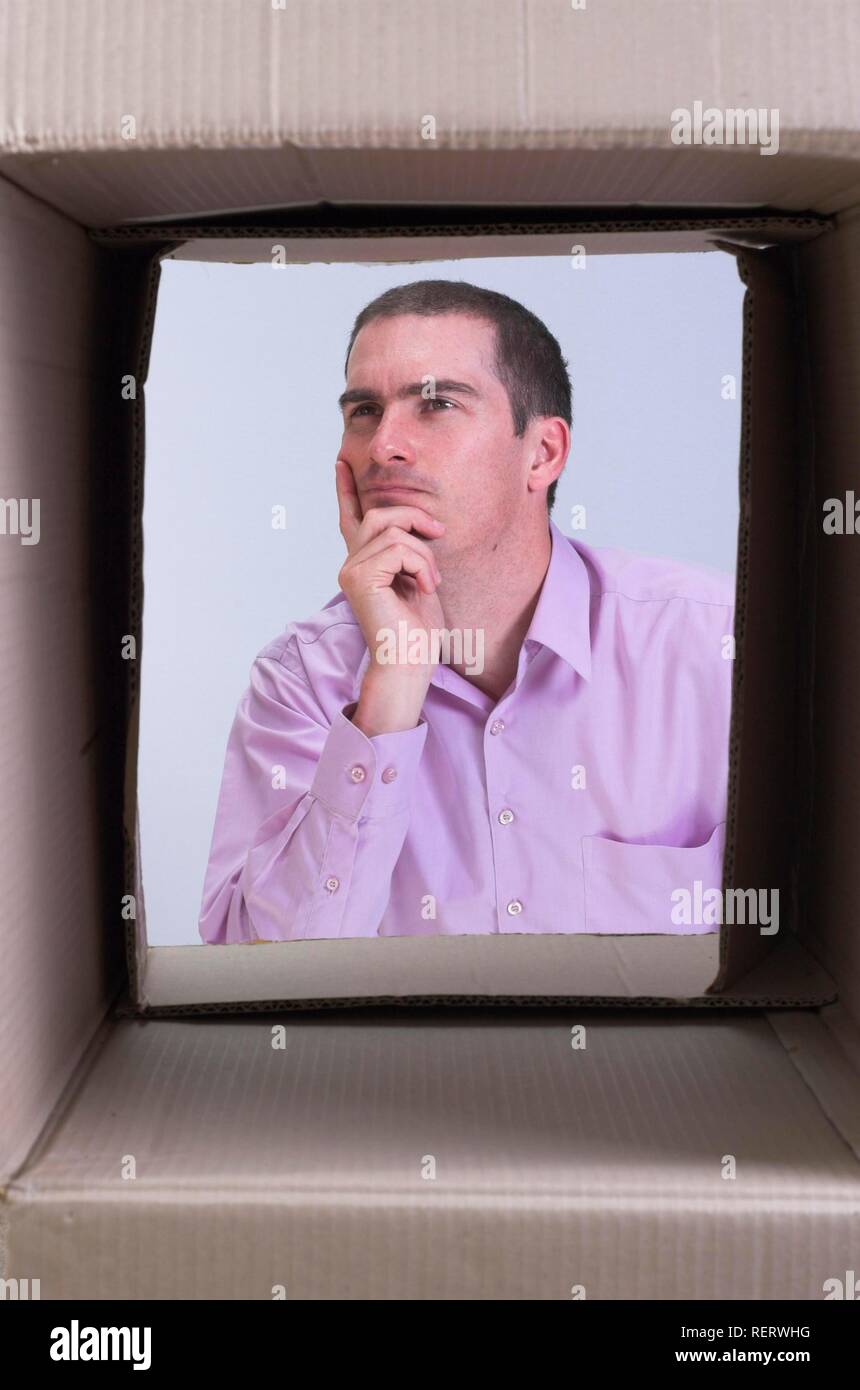 Nachdenkliche Menschen durch eine Box gesehen, symbolisch für Querdenken, kreatives Denken und Querdenken Stockfoto