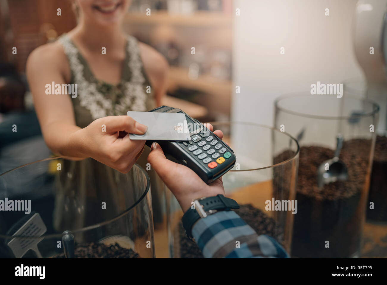 Hand des Kunden bezahlen mit kontaktlosen Kreditkarte mit der NFC-Technologie. Kellner mit einem credit card reader Maschine und mit weiblichen lächelnd Holding cre Stockfoto