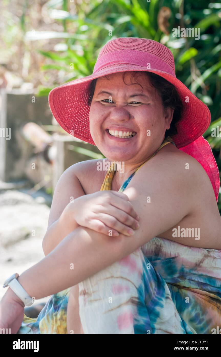 Ziemlich Filipino Frau tragen bunte Hut und Kleid lächelt, als Sie entspannt auf Lama Island, Hong Kong, bekannt für einen erholsamen, entspannten Lifestyle. Stockfoto