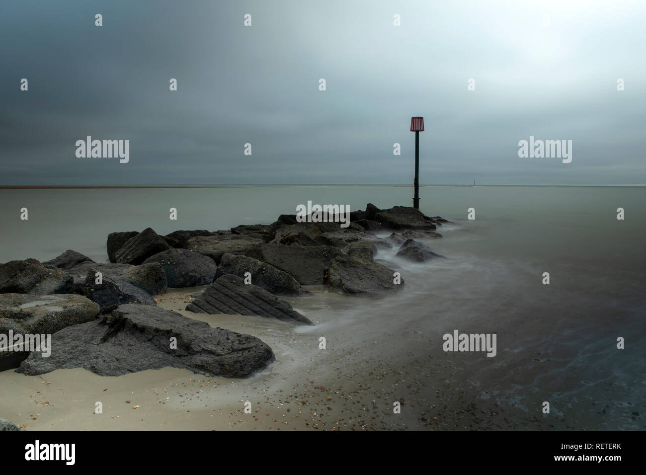 Lange Belichtung Wellen schlagen einer See Defense in Hayling Island Hampshire. Kalte Winter Tag mit grauem Himmel oben. Stockfoto