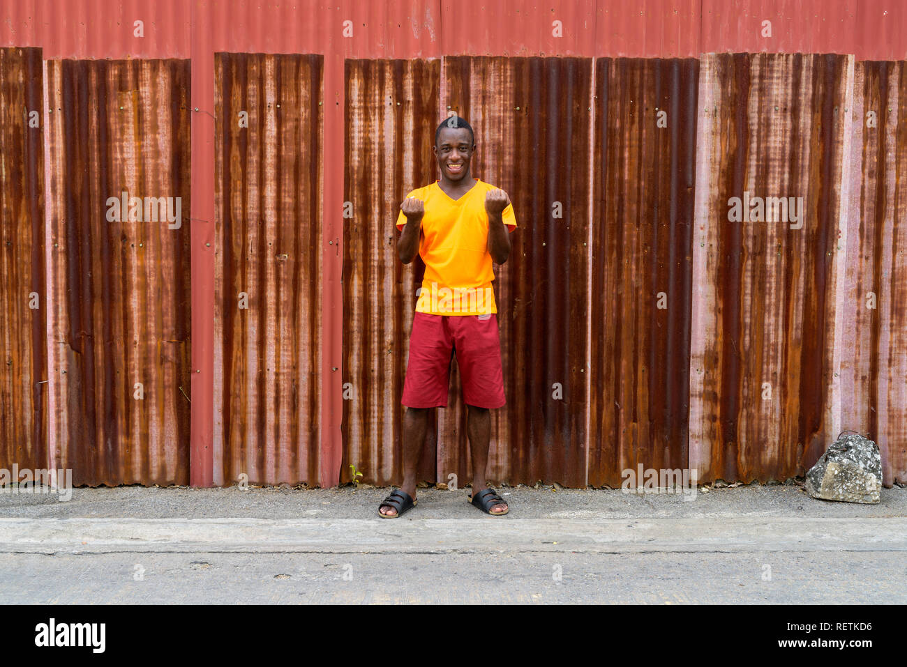 Junge glücklich schwarzen afrikanischen Mann lächelnd und Suchen während aufgeregt Stockfoto