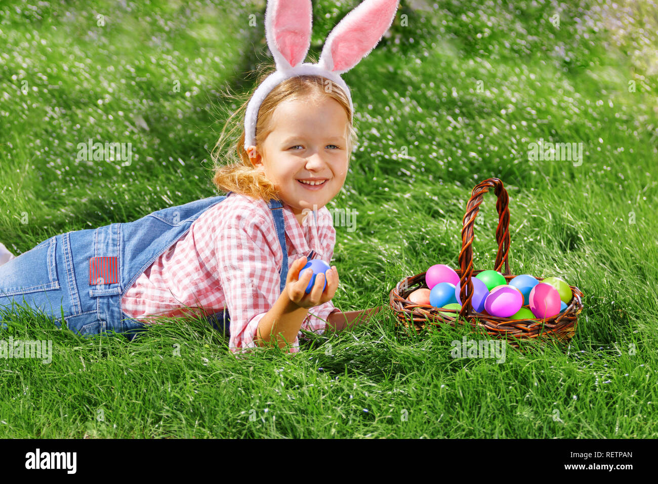 Glückliche kleine Mädchen Jagd Ostereier im Garten. Stockfoto