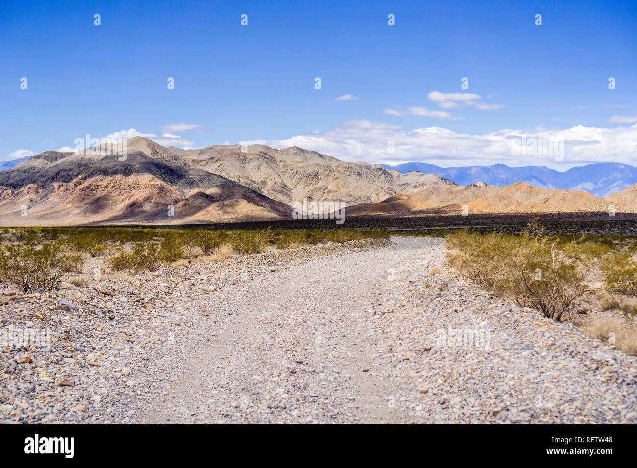 Reisen auf einer unbefestigten Straße durch eine einsame Gegend des Death Valley National Park; Berge und blauer Himmel im Hintergrund; Kalifornien Stockfoto