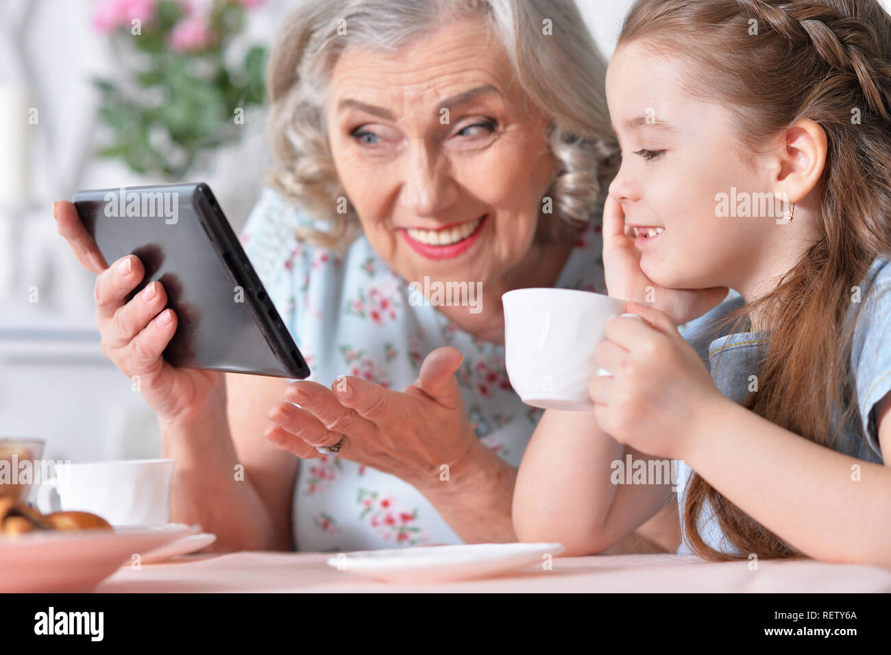 Süße kleine Mädchen mit ihrer Großmutter an Tablet suchen Stockfoto