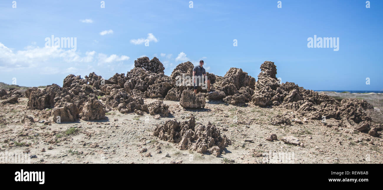 Junger Mann stehend auf den felsigen Hügel in Aruba. Stockfoto