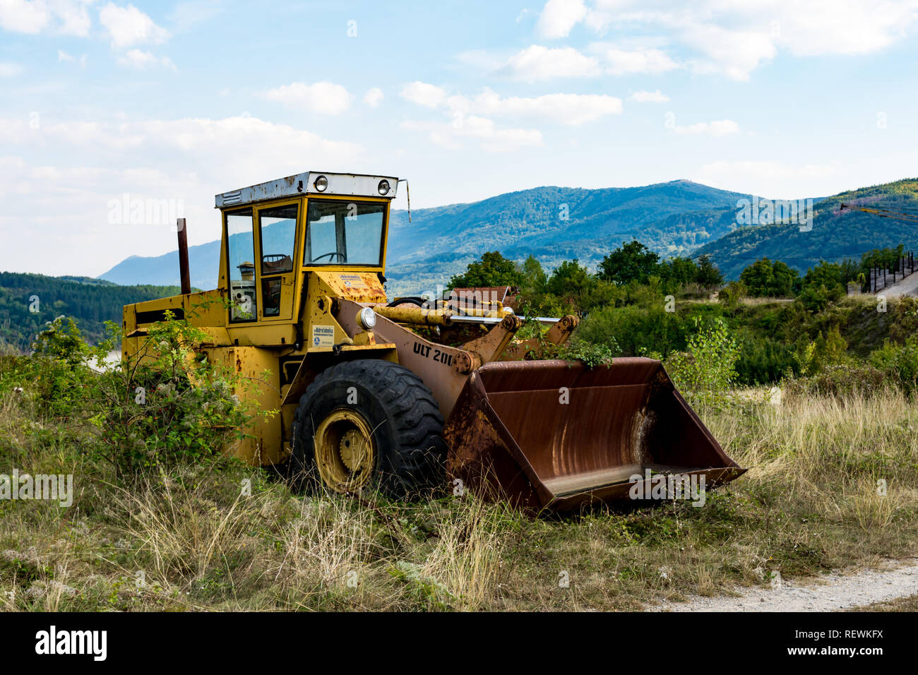 Alten, verlassenen unterbrochener gelber Bagger, in der Nähe vom See Zavoj, auf einer alten Berg. Rostig und mit der beschädigte Reifen widersetzte sich der Zahn der Zeit. Stockfoto