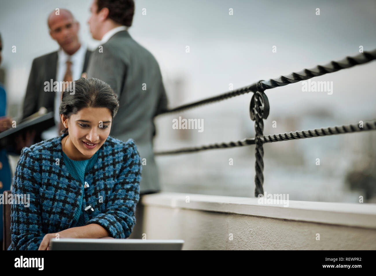 Junge Geschäftsfrau arbeitet auf Ihrem Laptop auf dem Balkon eines Corporate Gebäude. Stockfoto