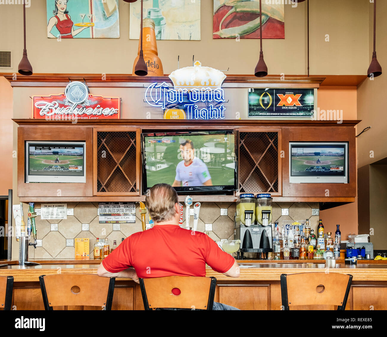 Single Mann oder männlichen Kunden allein sitzen an der Bar in einer Sports Bar Sport beobachten auf TV in Montgomery Alabama, USA. Stockfoto