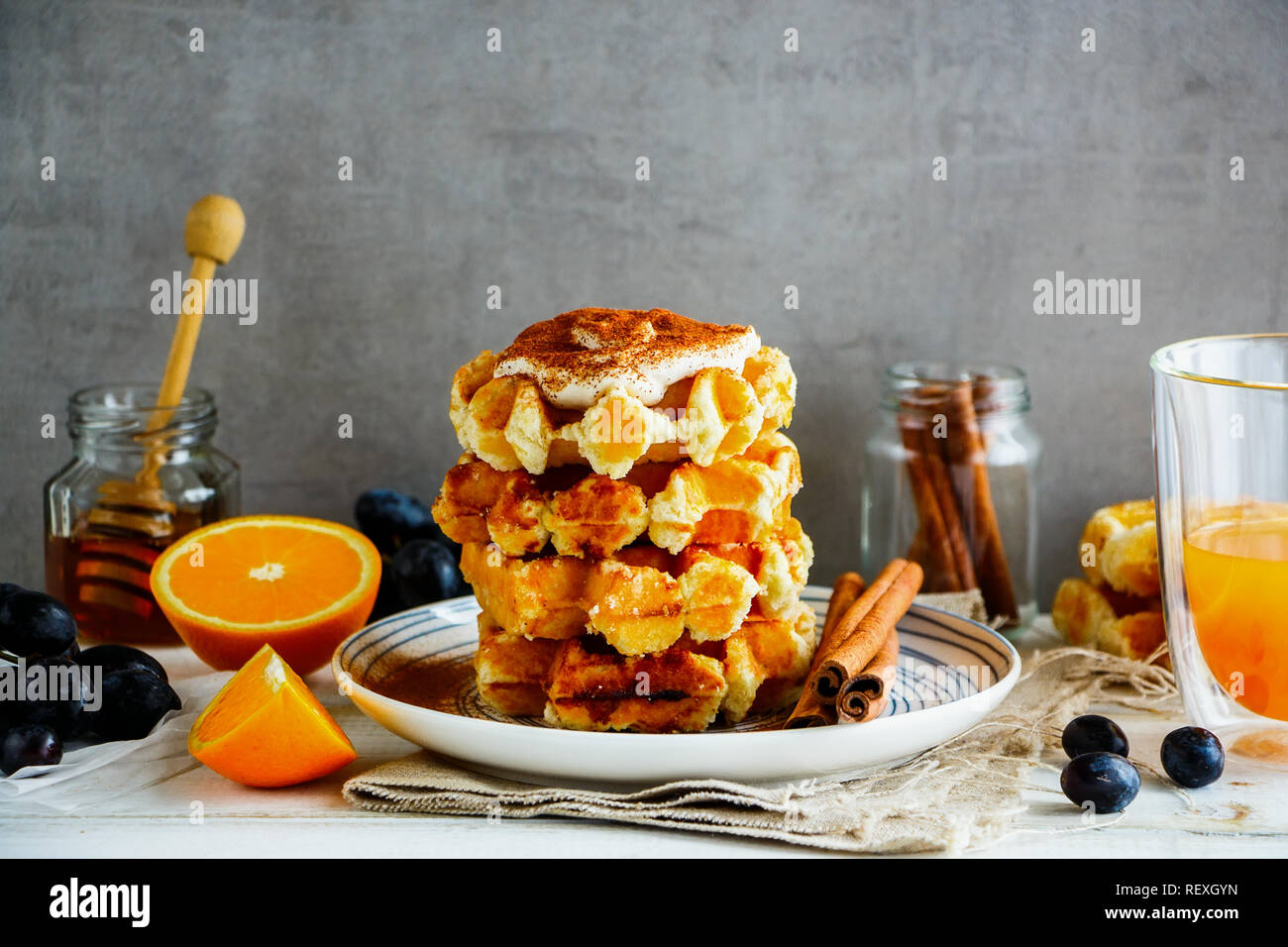 Verschiedene Früchte, Honig, Orangensaft und hausgemachte Zimt Waffeln mit Sahne Stockfoto