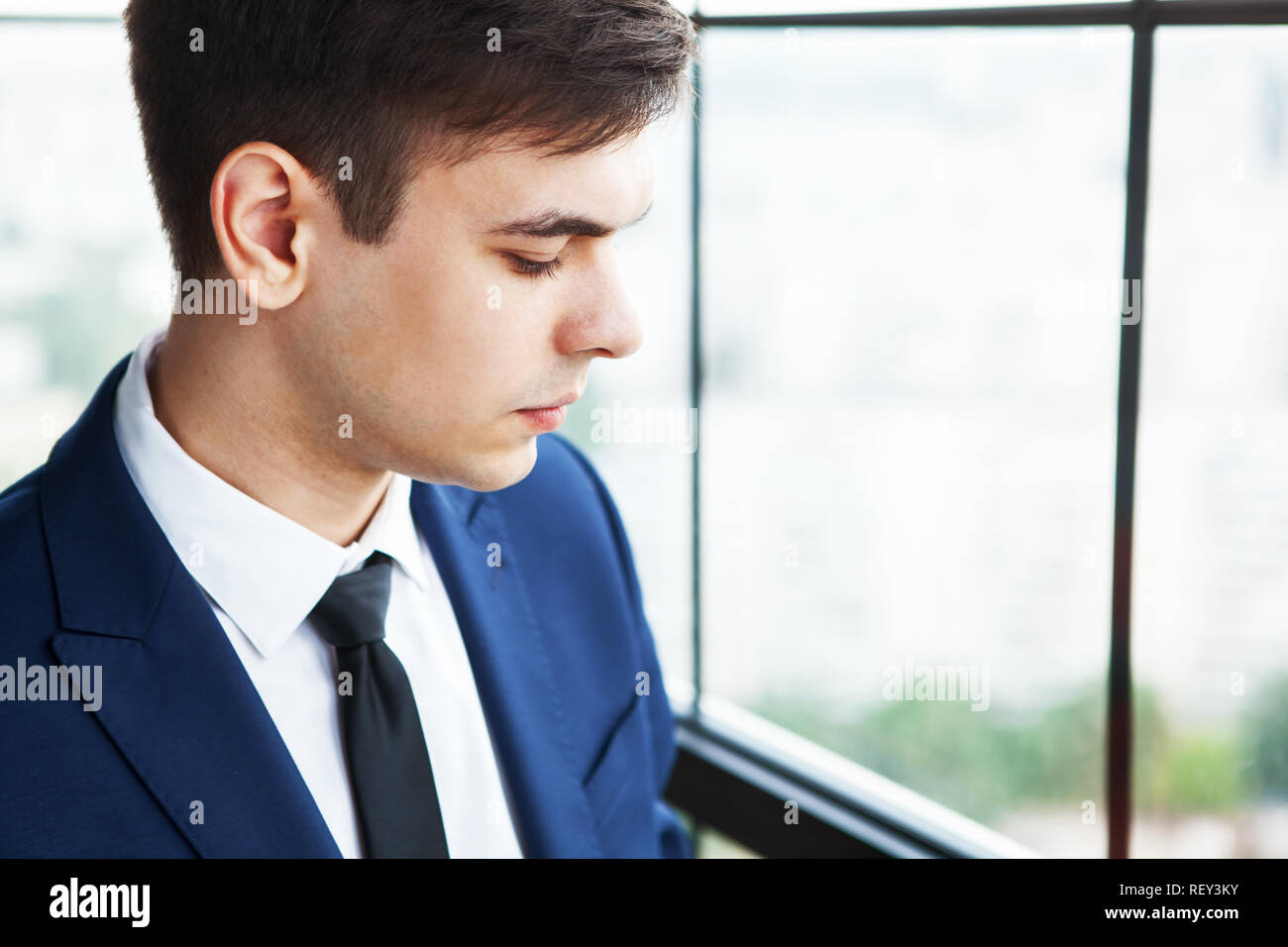Porträt einer umgekippt und Sorgen junger stattlicher Geschäftsmann stand in der Nähe der Fenster. Stockfoto
