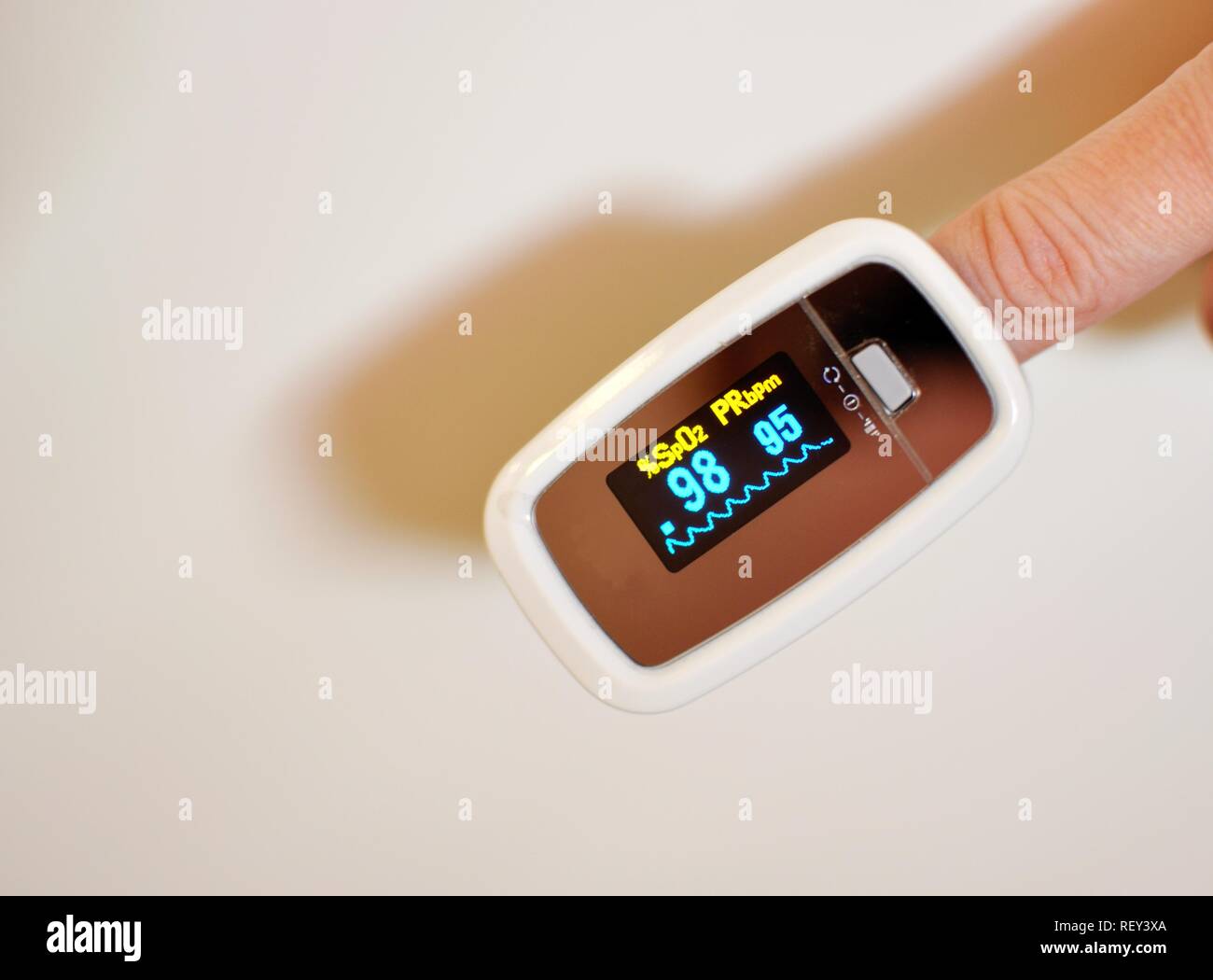 Blick von oben auf ein Digitales Pulsoximeter mit einem weißen Finger innen und eine elektronische Anzeige mit Messungen. Medizinisches Gerät. Stockfoto