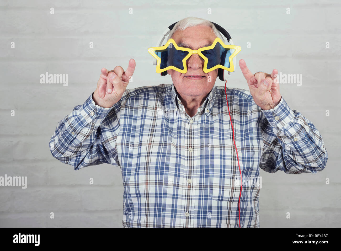Ältere Menschen mit Kopfhörern und lustigen Sonnenbrille auf Stein Hintergrund Stockfoto