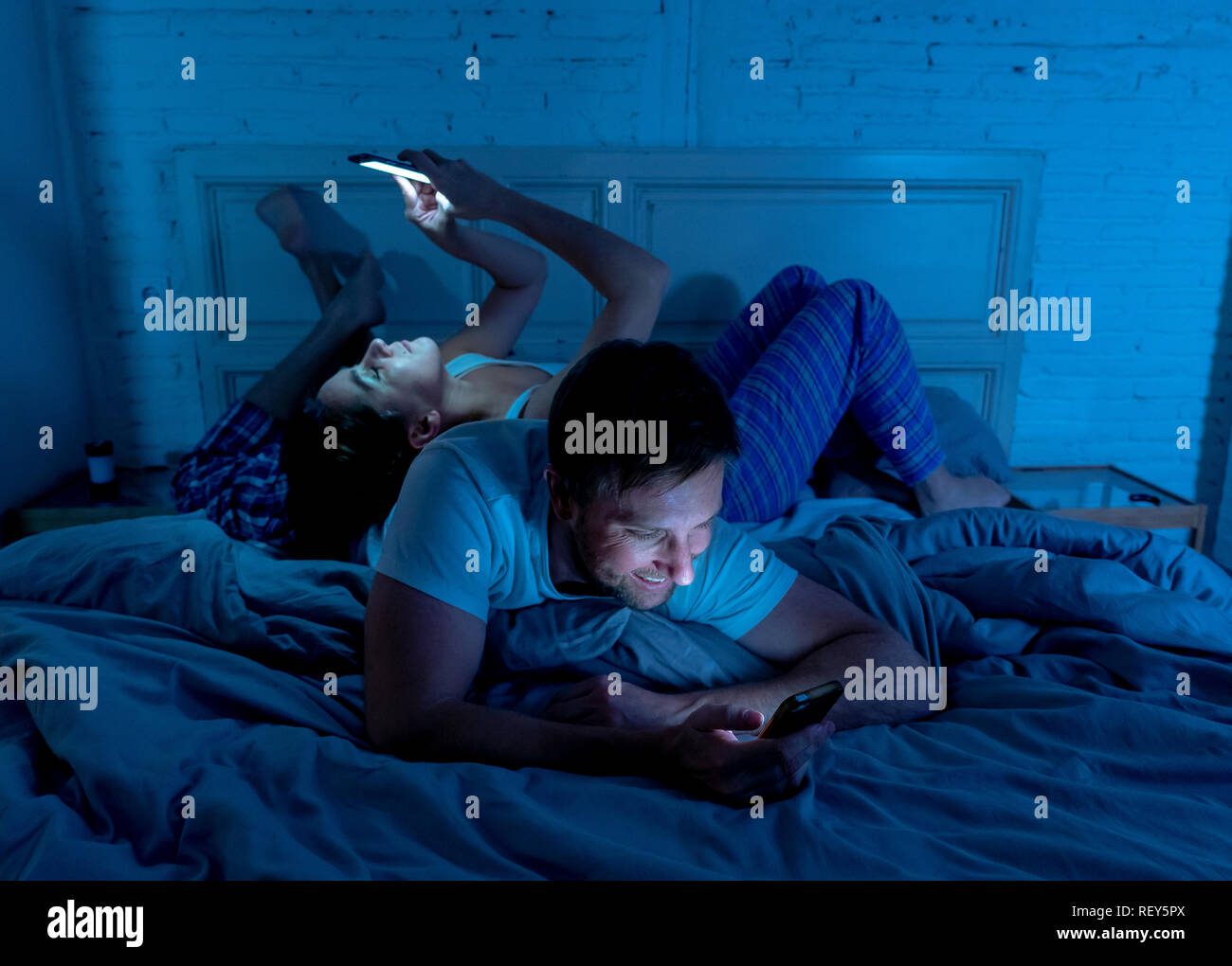 Traurige Mann und Frau Ehepaar mit Ihren smart Handy nachts im Bett gegenseitig ignorieren als Fremde in Beziehung und Kommunikation pro Stockfoto