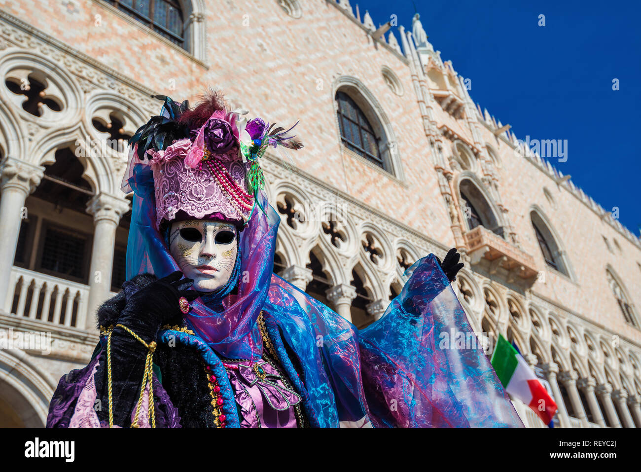 Karneval in Venedig. Eine Beautiufl venezianischen Karneval Maske mit der berühmten Dogenpalast adn italienische Flagge im Hintergrund Stockfoto