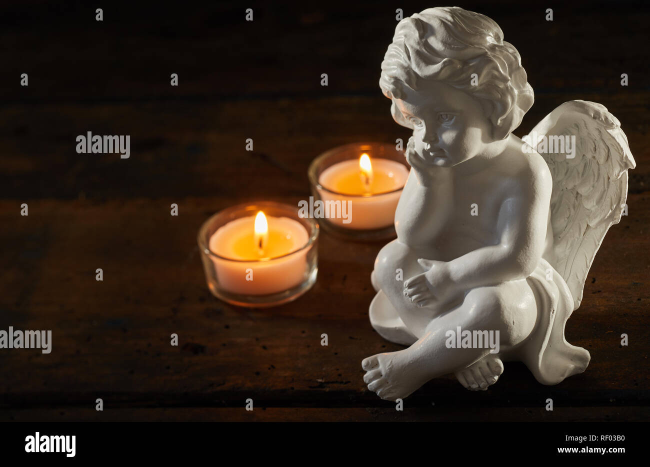 Engel Figur mit brennenden Kerzen auf einem dunklen Hintergrund mit Kopie  Raum konzeptionelle von Trauer und Verlust Stockfotografie - Alamy