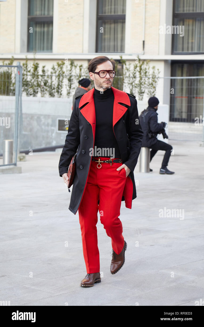 Mailand, Italien - Januar 12, 2019: Mann mit roten Hosen und schwarzen und roten Mantel vor Neil Barrett fashion show, Mailand Fashion Week street style Stockfoto