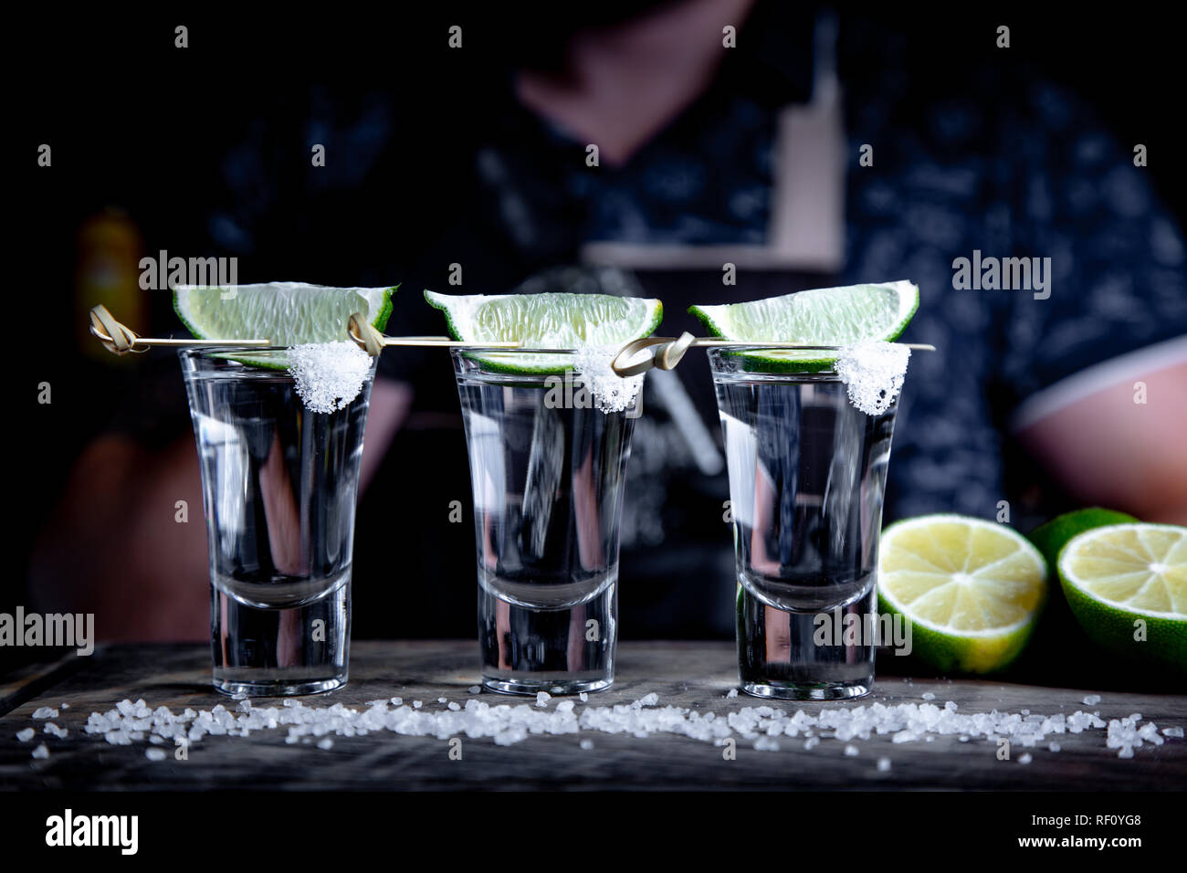 Aperitif mit Freunden in der Bar, drei Gläser Alkohol mit Kalk und Salz für die Dekoration. Tequila shots, selektiver Fokus Stockfoto