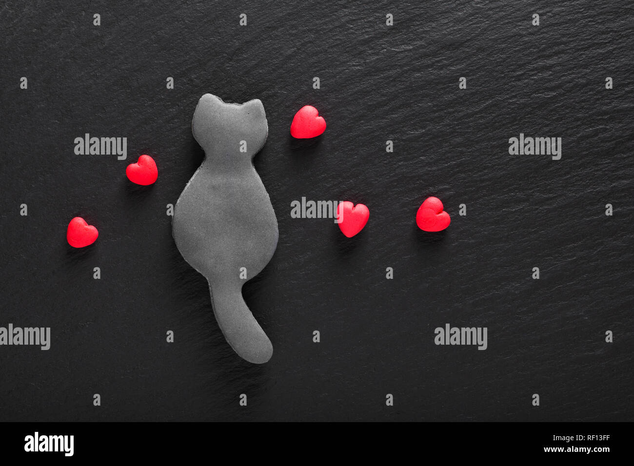 Valentine Hintergrund edibale genießbare Single black cat Cookies und Fondantzucker roten Herzen auf schwarzen Hintergrund mit Kopie Raum Stockfoto