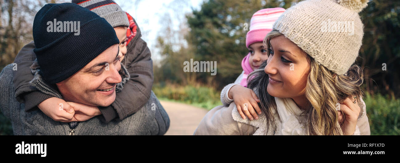 Eltern geben piggyback Ride auf glückliche Kinder im Freien Stockfoto