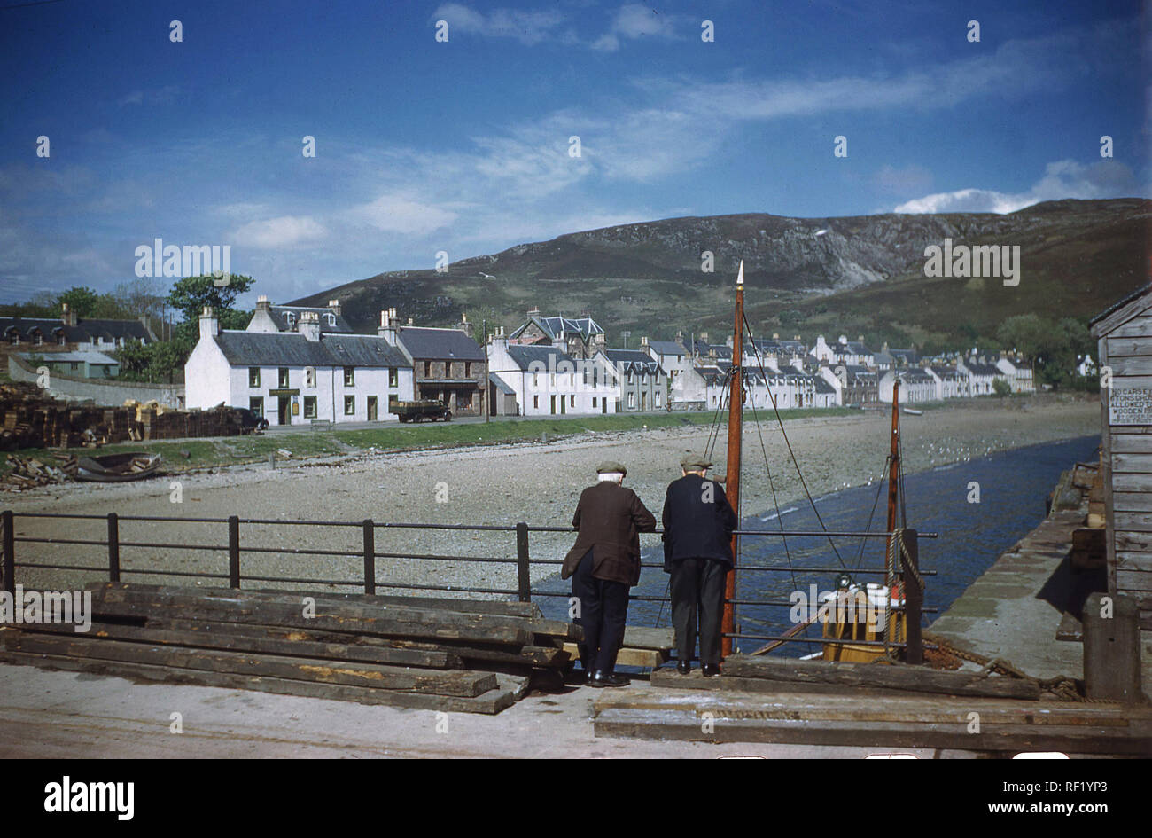 1960, historische, zwei Männer stehen auf einer Brücke am Hafen rückwärts suchen Dorf von Ullapool, Highlands, Schottland, UK auf Hochland. Stockfoto