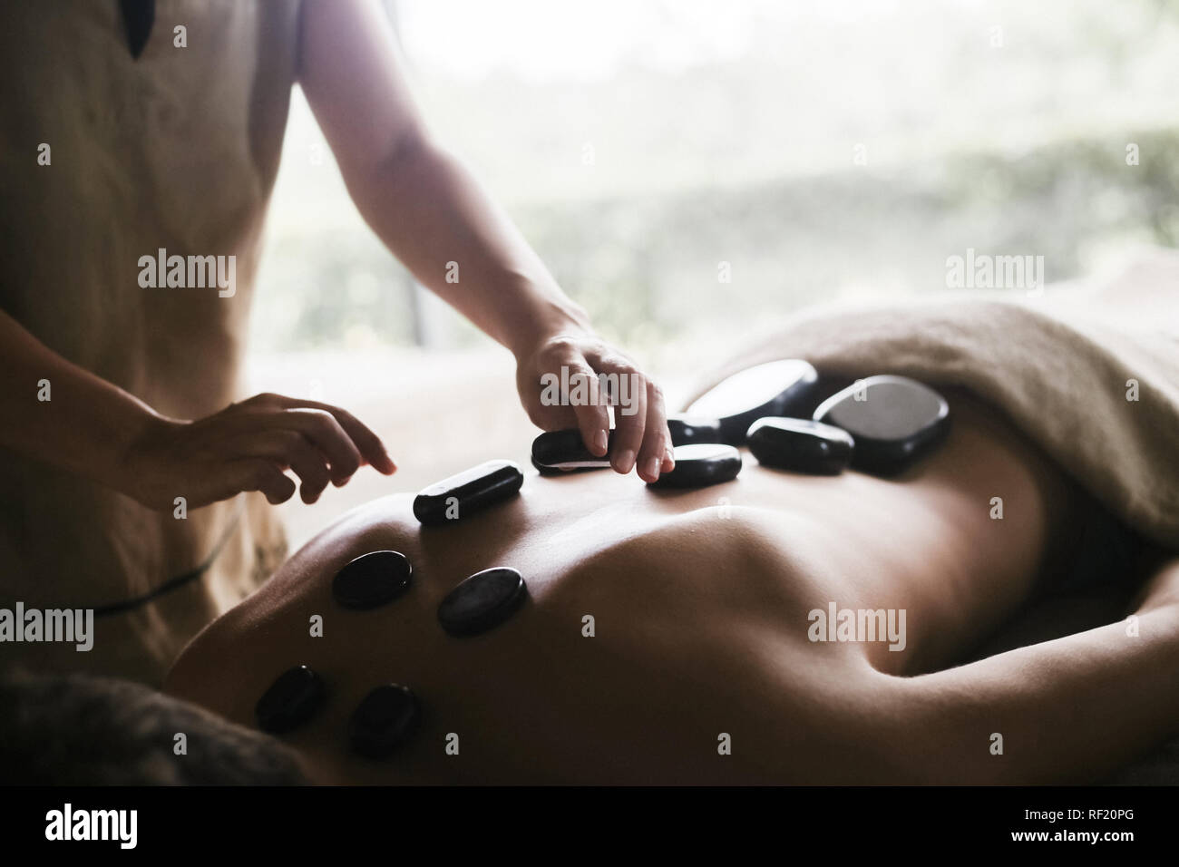 Mensch, der hatte eine Rückenmassage mit Öl und warmen Steinen Stockfoto