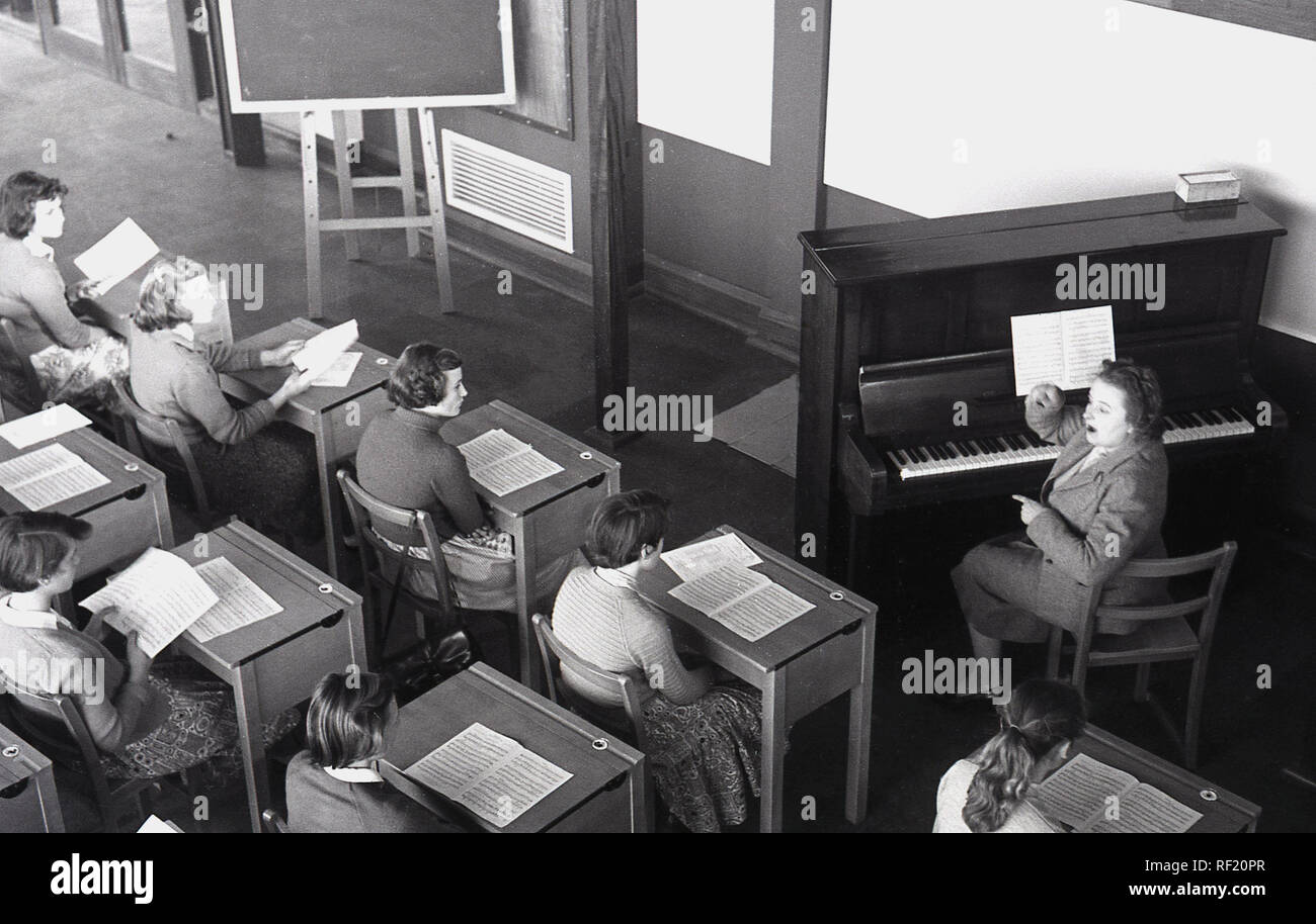 1956, historische, Lehrerin an ein Klavier, eine Musikstunde zu Schülerinnen an einer britischen Grafschaft Secondary School, England, UK sitzen Stockfoto