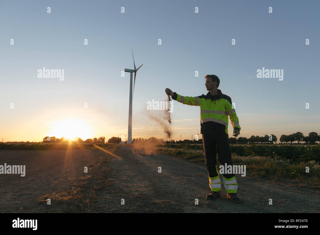 Ingenieur bei einer Windkraftanlage bei Sonnenuntergang Streuung Boden Stockfoto